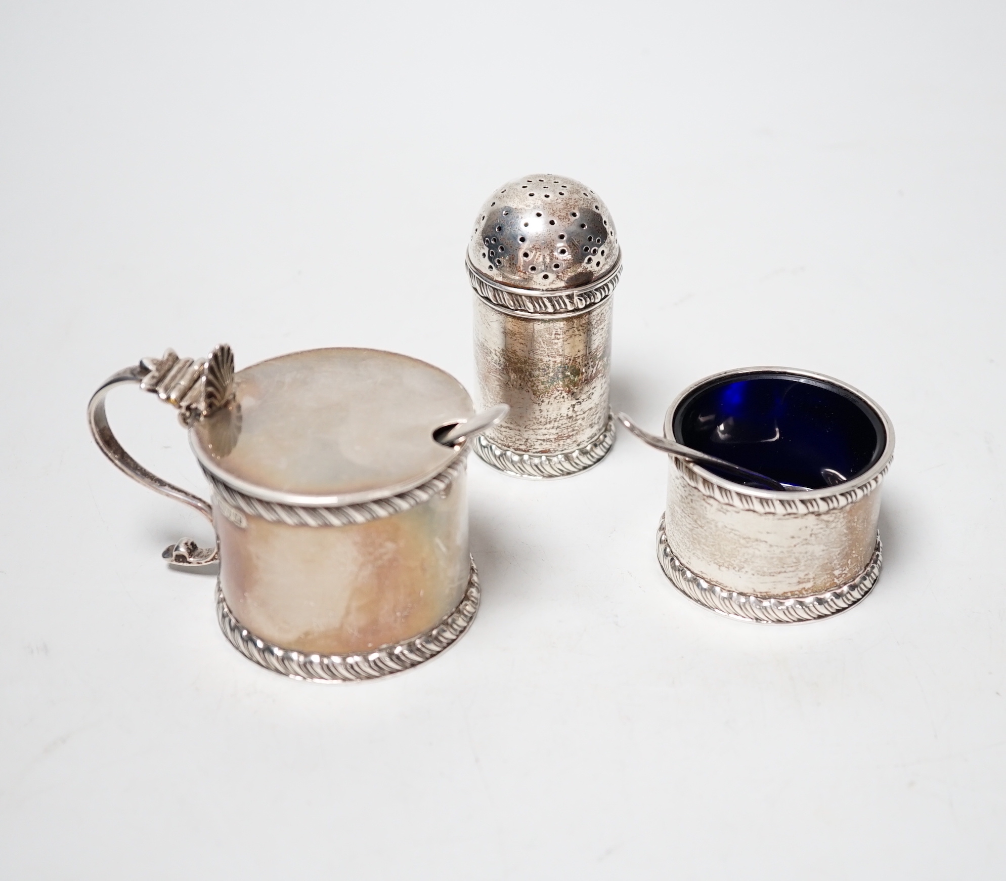 A George V three piece silver condiment set, Stokes & Ireland, Chester, 1923 and two associated spoons.